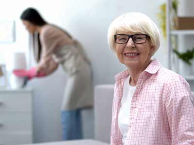 Aide à domicile en train de faire le ménage auprès d'une femme senior.