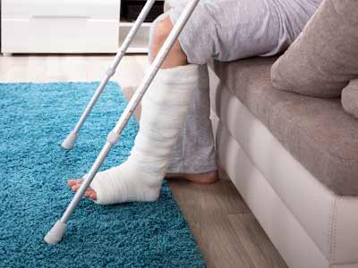 Personne avec la jambe dans le plâtre assis sur son sofa chez lui dans son salon.