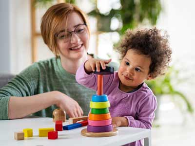 Jeune femme en train de jouer avec un jeune enfant à des jeux ludiques.