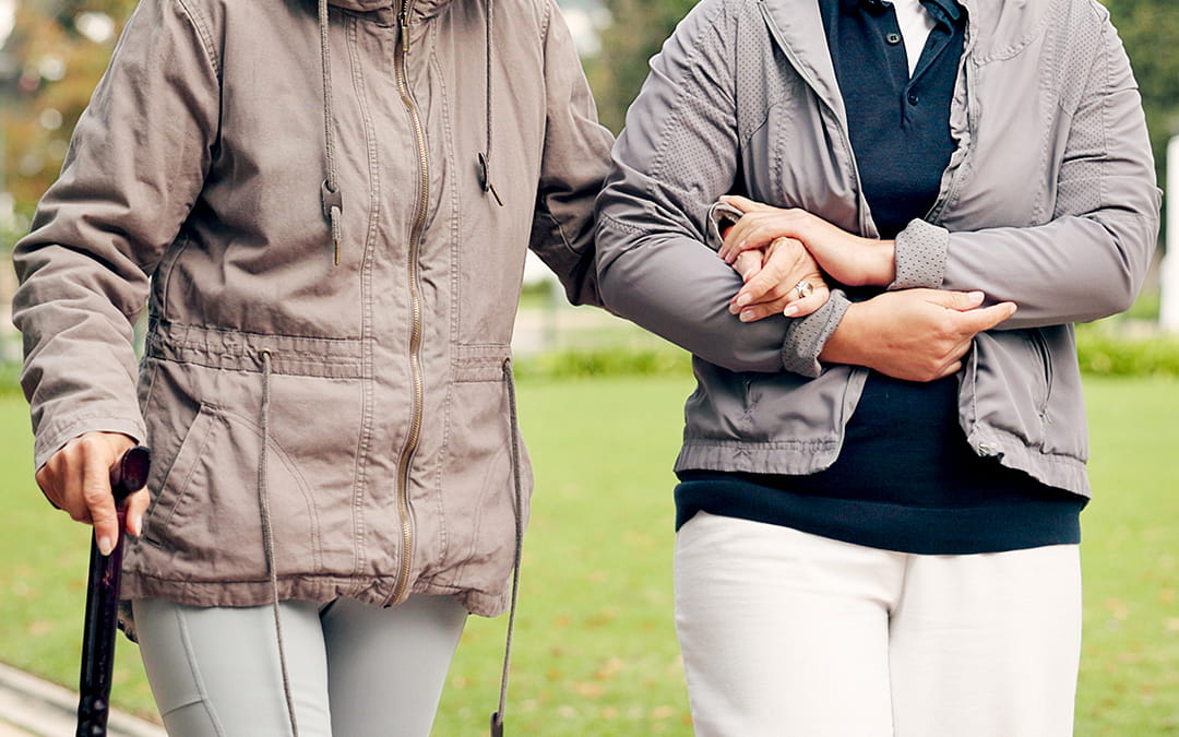 Aide personne âgée Monaco : femme âgée avec jeune auxiliaire de vie en promenade dans un parc.
